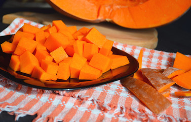 Fresh raw pumpkin on a diced board. Gray-orange background. Vegetarian cuisine.