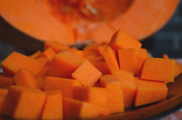 Fresh raw pumpkin on a diced board. Gray-orange background. Vegetarian cuisine.