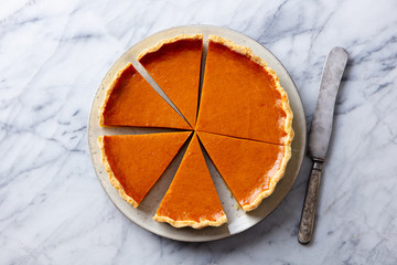 Pumpkin pie on a plate. Marble background. Close up. Top view.