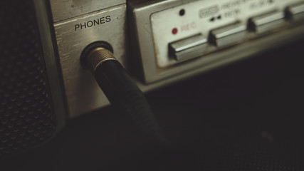 The old cassette player boombox headphone jack plugs into a headphone jack. Retro music concept.