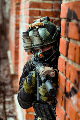 Closeup military man in black camouflage uniform aims aiming from around the corner.