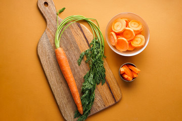 Ripe fresh and chopped carrot on a brown background. Flat lay composition