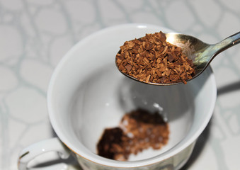 Granulated instant coffee in a spoon to pour into a mug.