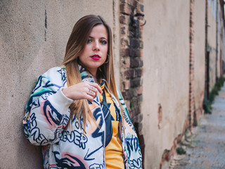a beautiful modern model with straight and long hair urban clothes with an old city wall