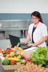 Portrait black long hair Asian pretty young woman nutritionist and note book computer with out of...