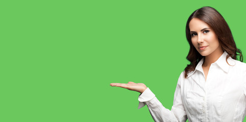 Young businesswoman, showing something or blank copy space area for slogan or text. Success in business concept. Green color background.
