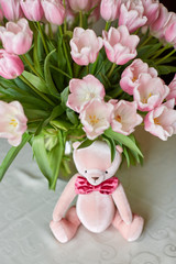 Pink bear toy and a vase with pink tulips on a table