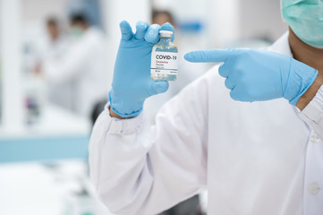 Fototapeta premium Doctor's hand holding bottle vaccine to patient in the hospital.Vaccination against coronavirus quarantine or covid-19.Protection against virus and infection control.Medication treatment concept.