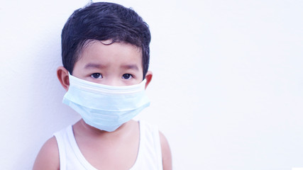 Portrait of cute little Asian 2 -3 years old toddler baby boy so sad face. Child wearing protective medical mask. Virus or PM 2.5 concept. 