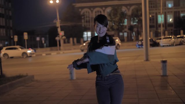 Very stylish asian girl dancing on a city street at night. Impressive Korean girl