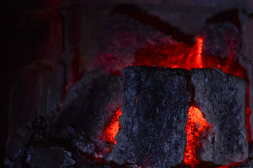 background with glowing coal from briquettes in a fireplace, the concept of home comfort and heating with ecologically clean fuel, copy space for text