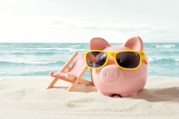 Fototapeta na wymiar Piggy bank on vacation. Finance and travel concept