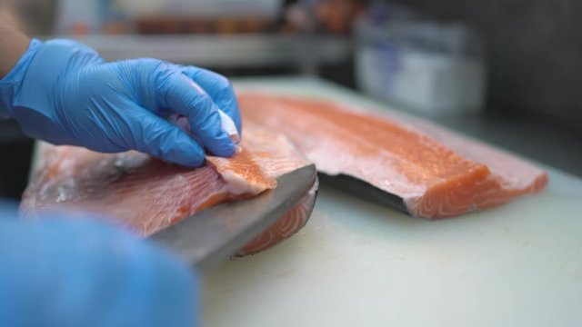 Scene of salmon fish cutting by good skill chef to prepare salmon meat for next process of fish bone remove to be sashimi, Fish cutting need to have skill and experience for prepare Japanese food.