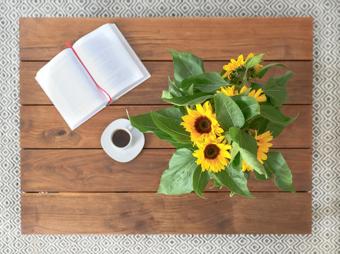 Sunflowers, book and cup of coffee. Still nature image top view.