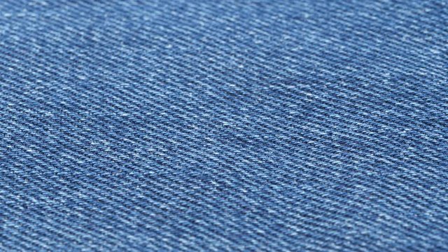 Jeans fabric close up tracking. Denim textile texture. Slider shot. Low angle, macro. 4K