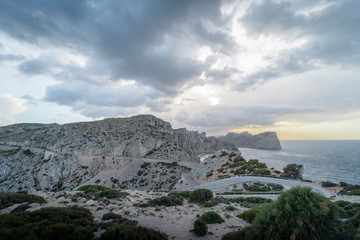 Fototapeta na wymiar Cloudy landscape of the winding road towards the lighthouse of Cabo de Formentor, on the coast of Pollensa, Mallorca