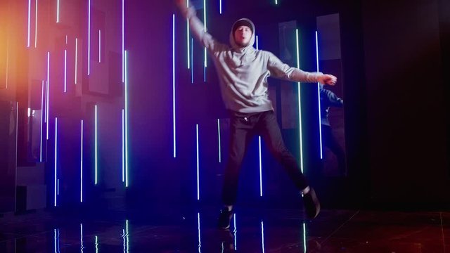 Billy Bounce dance. Funky activity. Guy performing freestyle movements in blue purple neon lights.