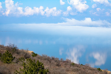 Fototapeta na wymiar fog above the lake, clouds at sky and its reflection in the water