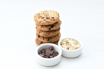 Oatmeal cookies and chocolate chips on light background