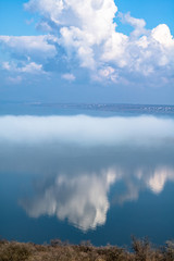 fog above the lake, clouds at sky and its reflection in the water