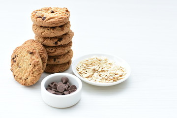 Oatmeal cookies and chocolate chips on light background
