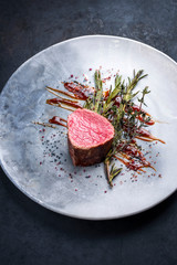 Barbecue dry aged beef fillet medallion steak natural with fried herbs and spice as closeup on a modern design plate with copy space