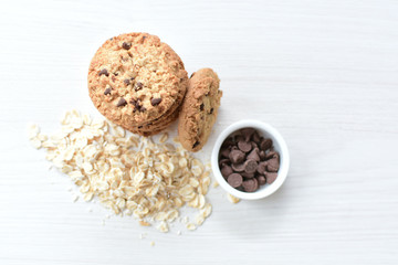Oatmeal cookies and chocolate chips on light background