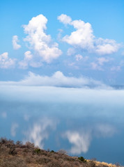 fog above the lake, clouds at sky and its reflection in the water