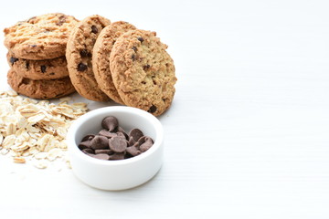 Oatmeal cookies and chocolate chips on light background