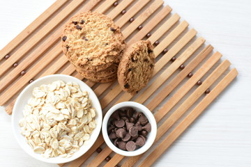 Oatmeal cookies and chocolate chips on light background