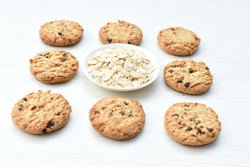 Oatmeal cookies and chocolate chips on light background