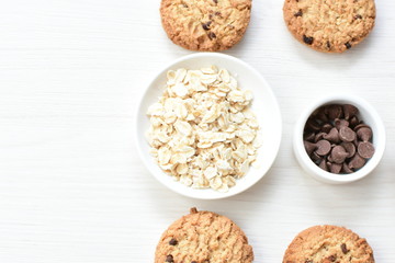 Oatmeal cookies and chocolate chips on light background