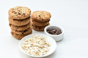Oatmeal cookies and chocolate chips on light background