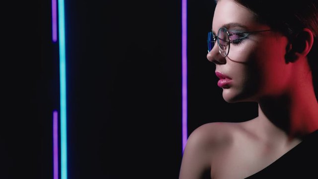 Neon model portrait. Fashion elegance. Woman wearing eyeglasses posing in blue purple lights.
