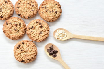 Oatmeal cookies and chocolate chips on light background