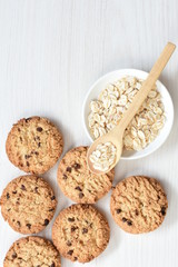 Oatmeal cookies and chocolate chips on light background