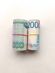 Different Russian rubles banknotes tied with rubber band, on a light background.