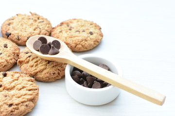 Oatmeal cookies and chocolate chips on light background