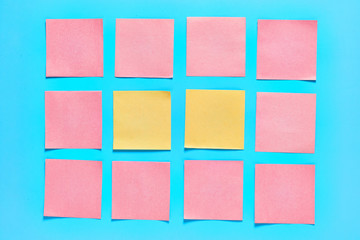 Two yellow and frame of pink square blank paper stickers on blue background. Copy space. Top view