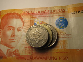 Different Philippines coins on banknote background.