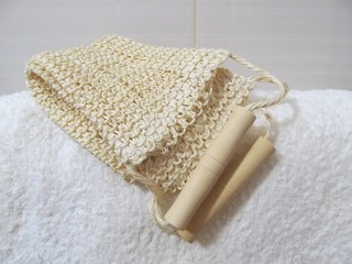 Body scrub sponge with wooden handles on the white towel