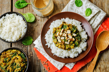 lentils, peanut butter spinach curry with rice on a wood background