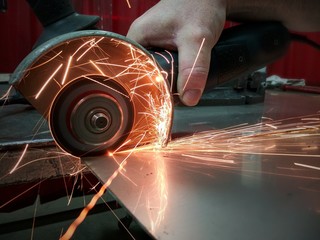 Worker cutting metal hand work angle grinder sparks.