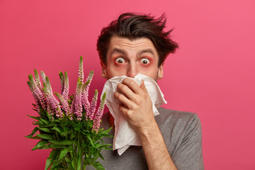 Man with allergy sneezes and covers nose with napkin, listens advice from allergist how to cure hay...