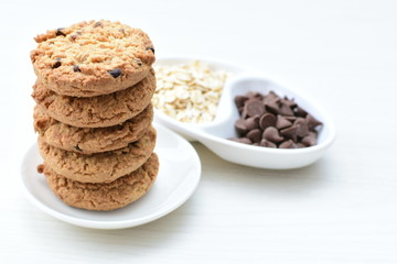 Oatmeal cookies and chocolate chips on light background