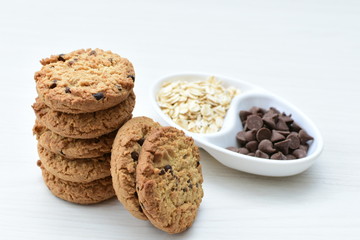 Oatmeal cookies and chocolate chips on light background