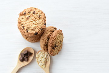 Oatmeal cookies and chocolate chips on light background