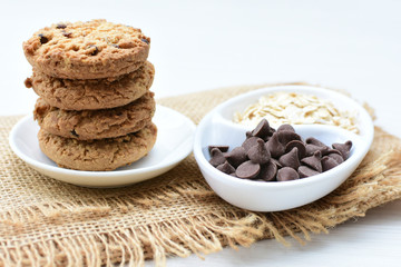 Oatmeal cookies and chocolate chips on light background