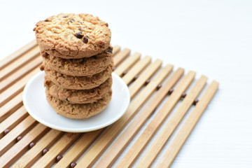 Oatmeal cookies and chocolate chips on light background