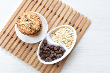 Oatmeal cookies and chocolate chips on light background